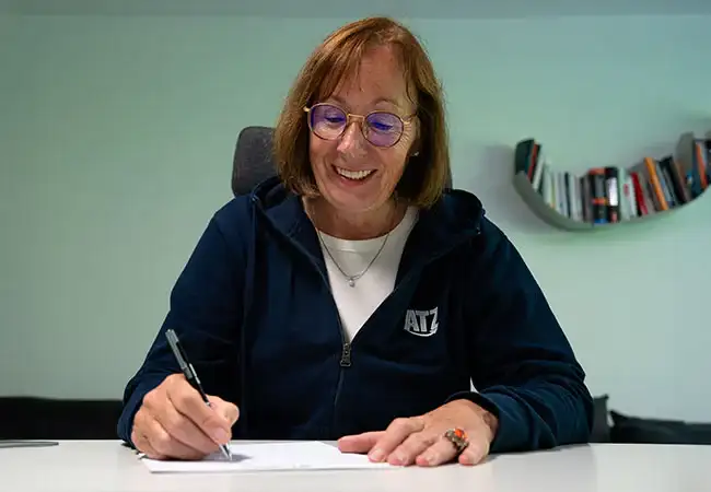 ATZ Group editor-in-chief smiling while writing something on paper