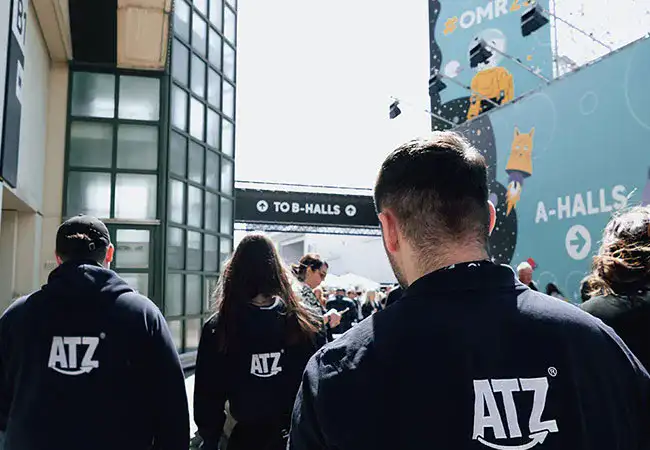 Three ATZ Group marketing employees walking towards the OMR trade fair