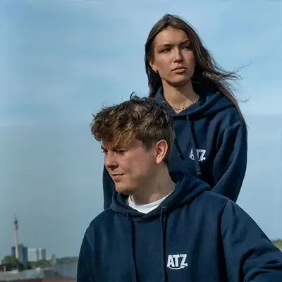 Two ATZ marketing employees posing in ATZ hoodies
